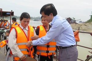 Ông Trần Văn Thọ, Phó Cục trưởng Cục ĐTNĐ Việt Nam hướng dẫn khách đi đò tại bến Dữu Lâu sử dụng áo phao cứu sinh. Ảnh: ATGT