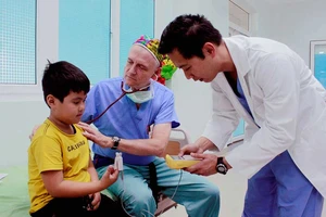 Bác sĩ James Nguyen và bác sĩ David Paul Norton (giữa) khám bệnh cho bé Ân tại Bệnh viện Sản nhi Quảng Ngãi