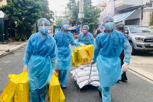 Đoàn viên thanh niên khu phố 1, phường Hòa Thạnh, quận Tân Phú đưa nhu yếu phẩm vào khu phong tỏa, trao tận tay người dân. Ảnh: VŨ TÂN