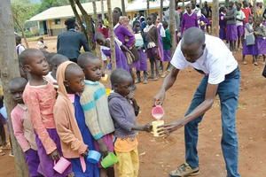 Trẻ em một trường học ở Kenya xếp hàng lấy cháo dinh dưỡng