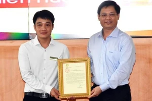 Phó Chủ tịch Thường trực UBND tỉnh Thừa Thiên - Huế Nguyễn Thanh Bình (bên phải) trao Thư khen của Chủ tịch nước cho anh Tô Vũ Đồng. Ảnh: NDO