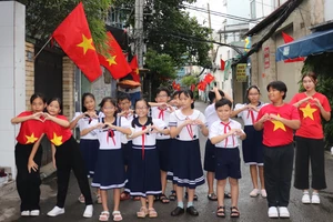 Các em thiếu nhi tạo dáng và bày tỏ niềm vui bên tuyến "Đường cờ Tổ quốc" đường Xóm Chiếu trong ngày ra mắt