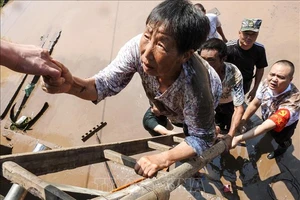 Nhân viên cứu hộ giúp sơ tán người dân khỏi các khu vực ngập lụt tại Dazhou, tỉnh Tứ Xuyên, Trung Quốc, ngày 12-7-2021. Ảnh: AFP/TTXVN
