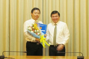 Chủ tịch UBND TPHCM Nguyễn Thành Phong (phải) trao quyết định và tặng hoa chúc mừng đồng chí Dương Anh Đức, Giám đốc Sở Thông tin và Truyền thông.