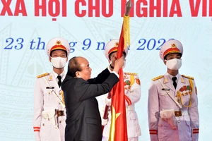 Chủ tịch Nước Nguyễn Xuân Phúc gắn Huân chương Lao động hạng Nhất lên lá cờ truyền thống của Ủy ban Quốc phòng và An ninh của Quốc hội. Ảnh: VIẾT CHUNG