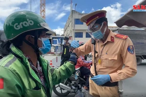 Lực lượng chức năng TPHCM kiểm tra một shipper trong ngày 26-7. Ảnh: VĂN MINH