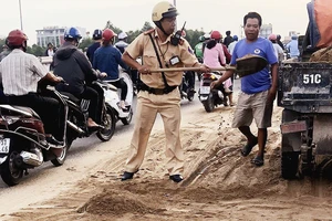 Cảnh sát giao thông - trật tự TPHCM dọn cát rơi trên đường