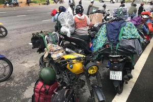 Gần 100 người đi xe máy chở theo hành lý, đồ đạc về quê được vận động ở lại TPHCM. Ảnh: C.T