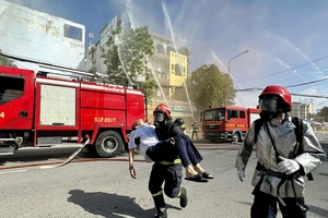 Lực lượng chữa cháy cứu người mắc kẹt trong các căn nhà ra ngoài chuyển cấp cứu. Ảnh: CHÍ THẠCH