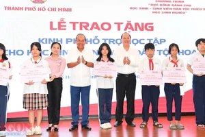 Phó Bí thư Thành ủy TPHCM Nguyễn Hồ Hải cùng nguyên Phó Thủ tướng Thường trực Trương Hòa Bình trao kinh phí hỗ trợ cho các em học sinh. Ảnh: VIỆT DŨNG 