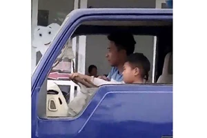 Thiếu niên hướng dẫn em bé 8 tuổi điều khiển xe tải (ảnh cắt từ clip)