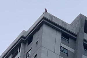 Người đàn ông ngồi cheo leo trên nóc tòa chung cư liên tục la hét