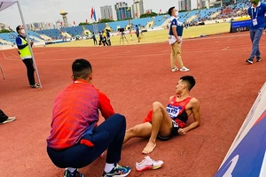 Nguyễn Tiến Trọng nhanh chóng giúp người đồng đội Trần Văn Đảng cởi giầy, sơ cứu ngay khi bị đau sau khi kết thúc thi đấu 800m. Ảnh: MINH CHIẾN