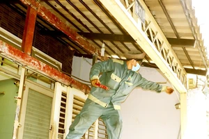 Laborers are working on a poorly installed scaffolding without any protective gears (Photo: SGGP)
