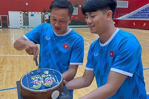 Trợ lý Nguyễn Tuấn Anh hỗ trợ đồng nghiệp Huỳnh Tấn Quốc cắt bánh mừng sinh nhật trên sân tập