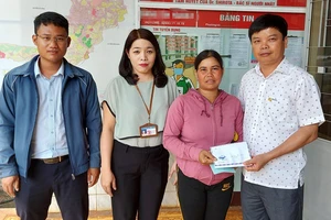 Ông Nguyễn Hữu Quế (bên phải), Chủ tịch UBND TP Pleiku phối hợp với đại diện Báo SGGP (bên trái) cùng UBND phường Trà Bá (thứ 2 từ trái qua) trao tiền hỗ trợ của bạn đọc Báo SGGP cho gia đình em Liên
