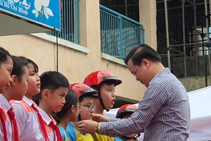 Thầy Trần Nguyễn Minh Thành trao tặng mũ bảo hiểm cho các em học sinh lớp 5 có hoàn cảnh gia đình khó khăn