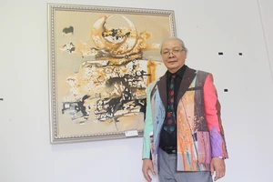 Họa sĩ Uyên Huy bên tác phẩm của mình tại triển lãm