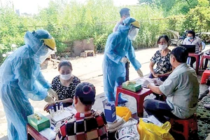 Nhân viên Trung tâm Y tế huyện Bình Chánh lấy mẫu xét nghiệm người dân tại tại chợ Tân Đoàn Việt - Phong Phú vào sáng 2-5. Ảnh: MINH NAM