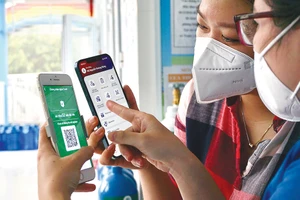 Chị Trần Thị Thanh Trang, huyện Bình Chánh, TPHCM hướng dẫn thành viên gia đình sử dụng app sổ sức khỏe điện tử trên nền điện thoại thông minh. Ảnh: HOÀNG HÙNG