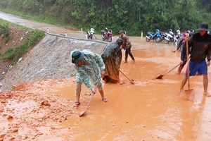 Bộ đội Biên phòng tỉnh Quảng Trị cùng người dân dọn bùn đất trên tuyến đường liên xã ở huyện Đakrông (Quảng Trị). Ảnh: NGUYỄN HOÀNG