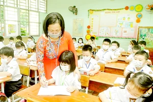 Học sinh lớp một Trường Tiểu học Nguyễn Đình Chiểu, quận Bình Thạnh, TPHCM được cô giáo hướng dẫn viết chữ trong ngày đầu học trực tiếp. Ảnh: CAO THĂNG
