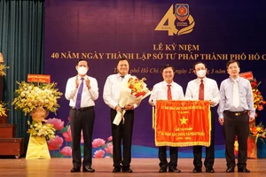 Bí thư Thành ủy TPHCM Nguyễn Văn Nên, Chủ tịch UBND TPHCM Phan Văn Mãi trao cờ truyền thống của UBND TPHCM cho Sở Tư pháp. Ảnh: MAI HOA