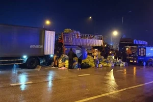 Người dân giúp đỡ tài xế bốc hàng tấn rau củ quả từ xe tải gặp nạn sang xe khác trong đêm tối mưa, lạnh