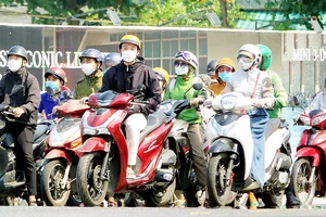 Người dân TP Đà Nẵng mặc áo khoác, trùm khẩu trang kín mặt để tránh nắng khi ra đường. Ảnh: XUÂN QUỲNH