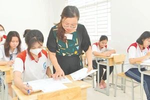Giám thị tại điểm thi Trường THPT Lương Văn Can, quận 8 (TPHCM) kiểm tra thông tin trên phiếu báo danh thí sinh. Ảnh: CAO THĂNG