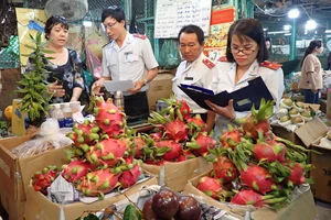 Thanh tra Ban Quản lý An toàn thực phẩm TPHCM kiểm tra một hộ kinh doanh trái cây tại chợ đầu mối nông sản Thủ Đức. Ảnh: HOÀNG HÙNG