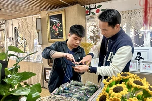 Nguyễn Lưu Quang, học sinh Trường Khiếm thính Lâm Đồng (bên trái), giới thiệu cho khách những sản phẩm do chính các bạn khiếm thính làm ra