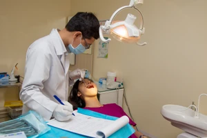 Bác sĩ nha khoa đang kiểm tra răng miệng cho một người bệnh. Ảnh: HOÀNG HÙNG