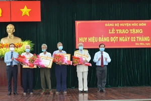 Đồng chí Trần Lưu Quang (bìa trái) tặng hoa chúc mừng các đảng viên 60 năm, 55 tuổi Đảng