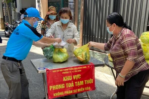 Người dân tại điểm phong tỏa phường 12, quận Tân Bình nhận hàng từ các địa phương hỗ trợ