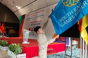 Nhân viên ở Trung tâm báo chí SEA Games 31 căng chỉnh lại cờ Đại hội. ẢNH: DŨNG PHƯƠNG