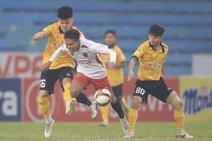 Các cầu thủ Hòa Bình (áo vàng) đầy vất vả ở trận đấu gặp đội khách Long An. ẢNH: MINH HOÀNG 