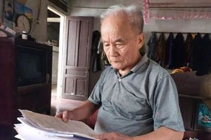 Ông Vương Khả Khai bên tập giấy tờ ghi chép tìm kiếm phần mộ liệt sĩ