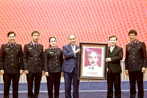 Chủ tịch nước Nguyễn Xuân Phúc trao bức chân dung Chủ tịch Hồ Chí Minh cho ngành kiểm sát nhân dân. Ảnh: QUANG PHÚC