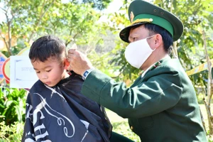 Người lính quân hàm xanh cắt tóc cho trẻ em Vân Kiều, bản Rum Ho, xã Kim Thủy, huyện Lệ Thủy để đón tết
