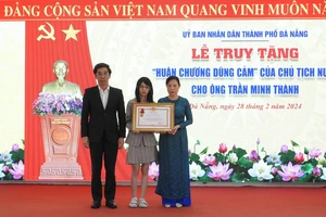 Thừa uỷ quyền của Chủ tịch nước, Phó Chủ tịch TP Đà Nẵng Trần Chí Cường truy tặng Huân chương Dũng cảm cho vợ và con gái ông Thành. Ảnh: DOÃN HÙNG