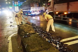 Cảnh sát giao thông hỗ trợ công nhân vệ sinh thu dọn vỏ chai đổ trên đường