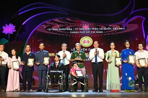 Chairman of the municipal People’s Committee Phan Van Mai (4th, R) and Vice Secretary of the Party Committee cum Chairman of the Vietnam Fatherland Front Committee of the city Nguyen Phuoc Loc (5th, L) honor individuals and collectives for their silent outstanding contributions to the social community in the city. (Photo: SGGP)