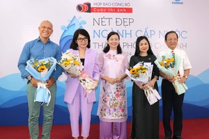 Tổng Biên tập Báo Phụ nữ TPHCM Lý Việt Trung (giữa) tặng hoa đến các thành viên Ban giám khảo cuộc thi 
