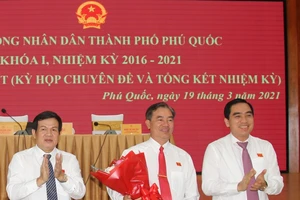 Chủ tịch HĐND TP Phú Quốc Nguyễn Đức Kỉnh (trái) và Chủ tịch UBND TP Phú Quốc Huỳnh Quang Hưng (phải) tặng hoa chúc mừng ông Đoàn Văn Tiến. ẢNH: HOÀNG DUNG