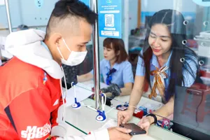 Nhân viên ngành cấp nước hướng dẫn người dân cài app SAWACO CSKH tại quầy giao dịch