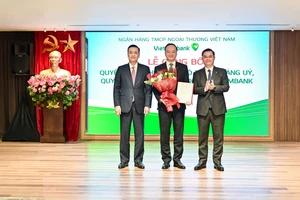 Ông Phạm Quang Dũng, Ủy viên Ban Thường vụ Đảng ủy, Phó Thống đốc NHNN (ngoài cùng bên trái) và ông Nguyễn Thanh Tùng, Ủy viên BCH Đảng bộ Chính phủ, Bí thư Đảng ủy, Chủ tịch HĐQT Vietcombank (ngoài cùng bên phải) trao quyết định và tặng hoa chúc mừng ông Lê Quang Vinh - tân Tổng Giám đốc Vietcombank