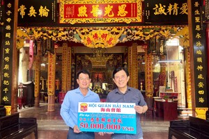 海南会馆理事长林明辉（右）向《西贡解放报》执行编辑文忠孝（左）移交5000万元赞助经费。