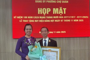 胡志明市左关坊党委常务副书记胡氏竹江祝贺华人退休干部梁鸿德荣获30年党龄纪念章。