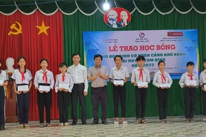 Ông Trần Trọng Dũng, Phó Chủ tịch Hội Nhà báo Việt Nam (giữa) và ông Hồ Việt Anh, Giám đốc Agribank - CN Vĩnh Long trao học bổng cho học sinh xã Loan Mỹ